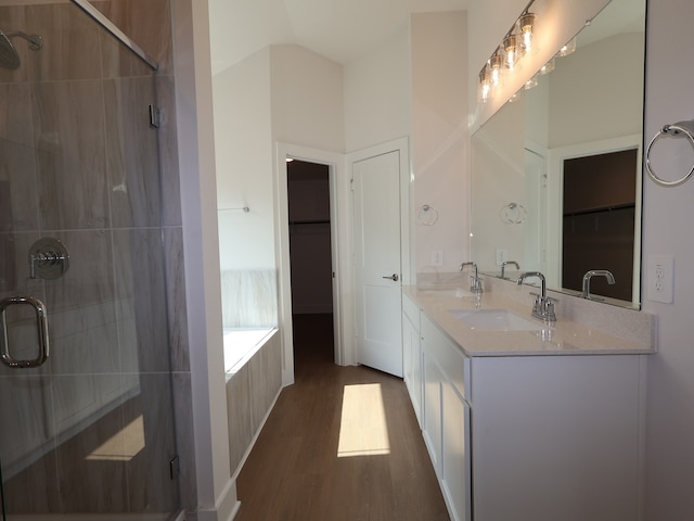full bath featuring a sink, a walk in closet, a stall shower, and wood finished floors