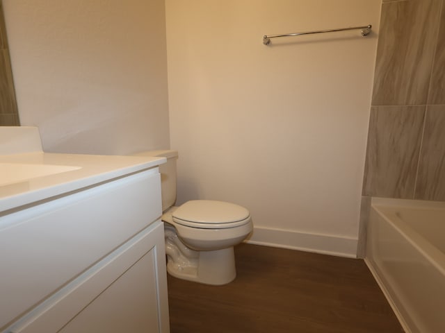bathroom with toilet, baseboards, wood finished floors, and vanity