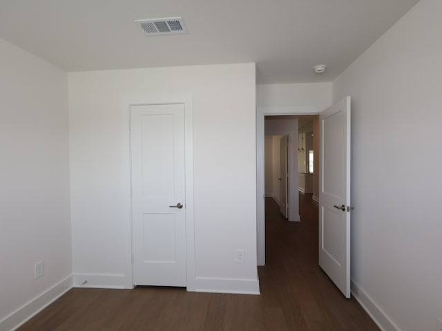 unfurnished bedroom featuring visible vents, baseboards, and dark wood-type flooring