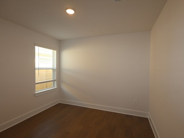 empty room featuring baseboards and dark wood-type flooring