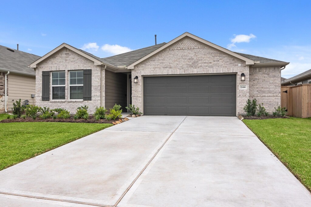 22486 Birchfield Grove Ln, New Caney, TX 77357 - ranch-style home featuring a garage, driveway, brick siding, and a shingled roof