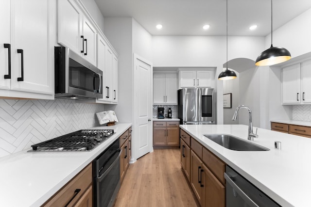 kitchen with white cabinetry, sink, hanging light fixtures, and appliances with stainless steel finishes