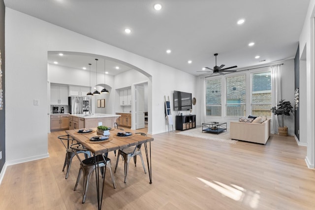 dining area with light wood-type flooring and ceiling fan