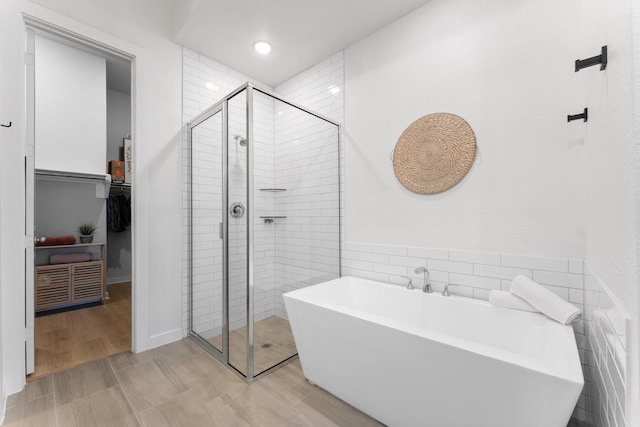 bathroom with separate shower and tub, wood-type flooring, and tile walls