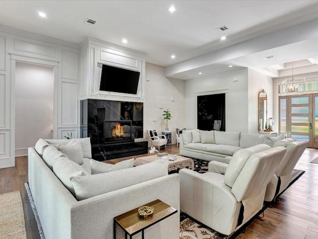 living room featuring hardwood / wood-style flooring, a notable chandelier, and a fireplace