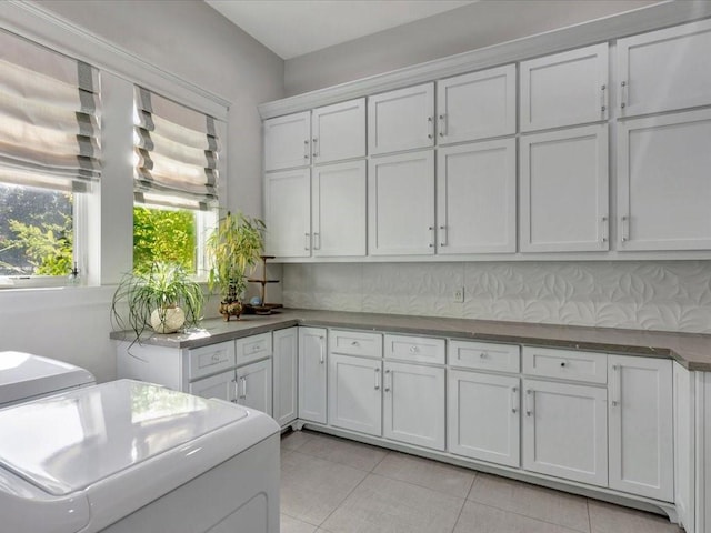 laundry area featuring cabinets, light tile patterned floors, and washer and clothes dryer