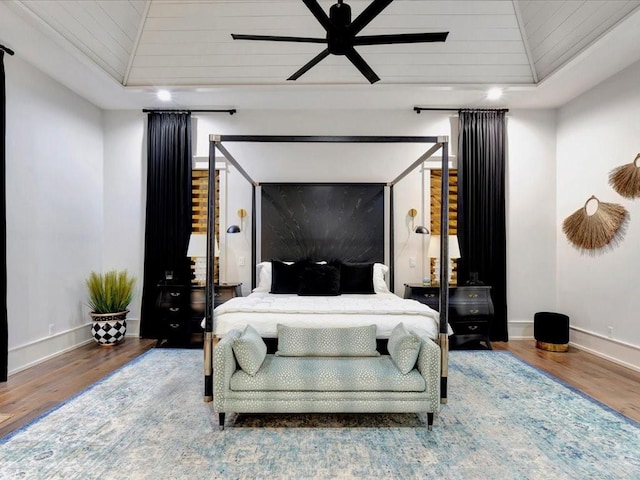 bedroom featuring wood-type flooring, a raised ceiling, ceiling fan, and wooden ceiling