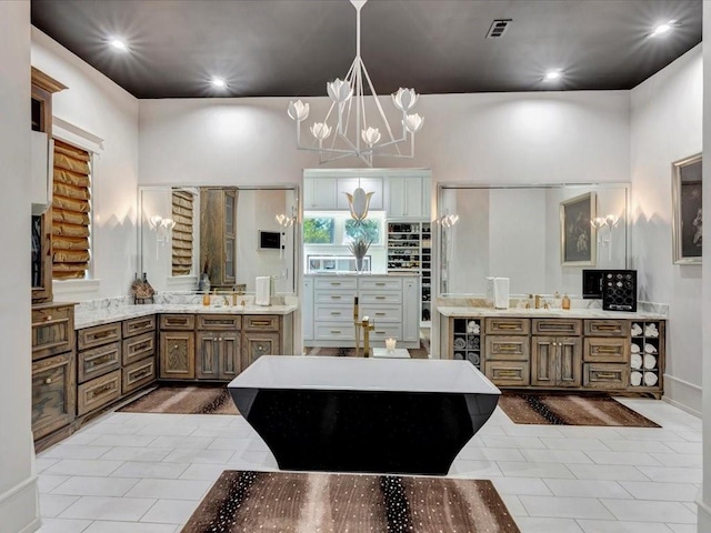 kitchen featuring light stone countertops, sink, pendant lighting, and a notable chandelier