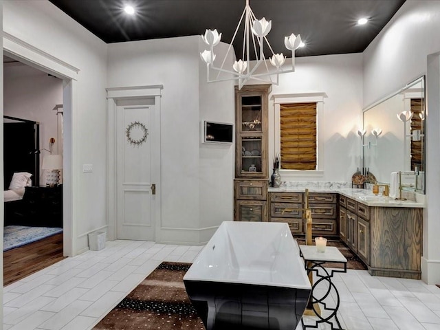 bathroom featuring a chandelier, wood-type flooring, vanity, and a tub to relax in