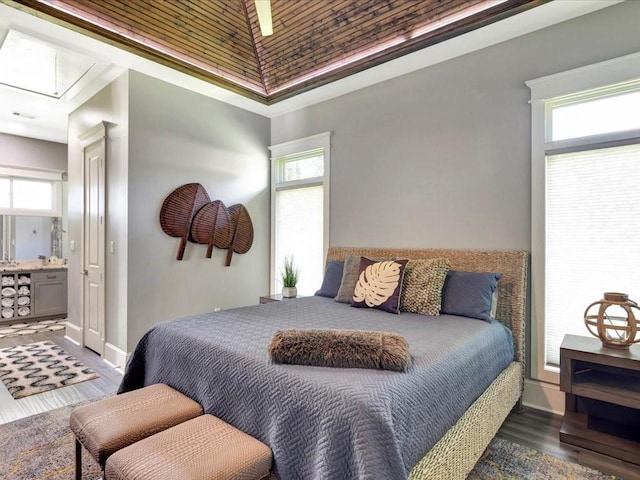 bedroom featuring ensuite bath, wood-type flooring, and multiple windows