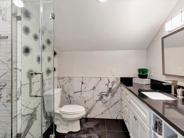 bathroom with tile patterned floors, vaulted ceiling, toilet, vanity, and tile walls