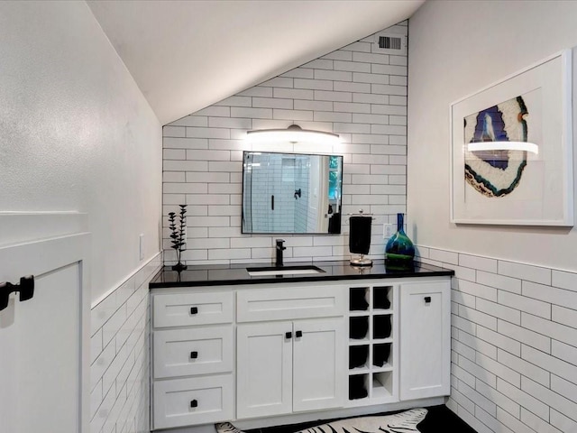 bathroom with tile walls, vanity, and vaulted ceiling