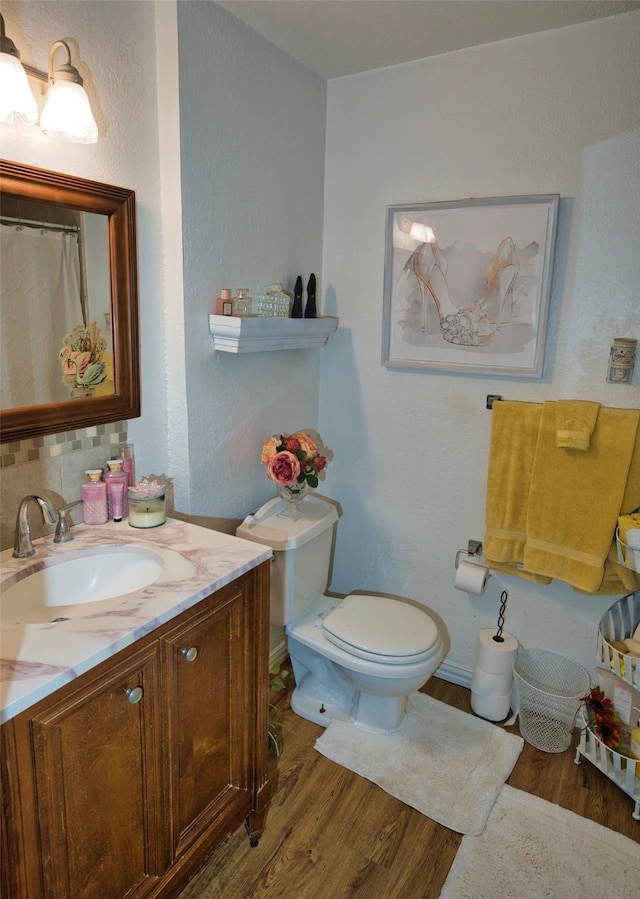 bathroom featuring decorative backsplash, vanity, wood-type flooring, and toilet