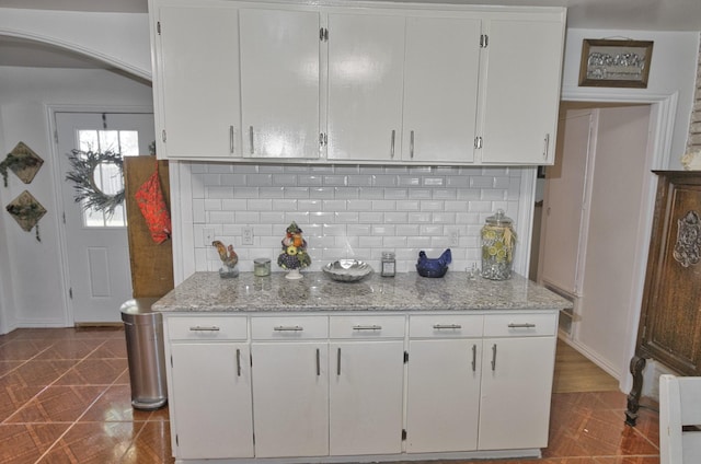 kitchen featuring tile patterned floors, light stone countertops, white cabinetry, and tasteful backsplash