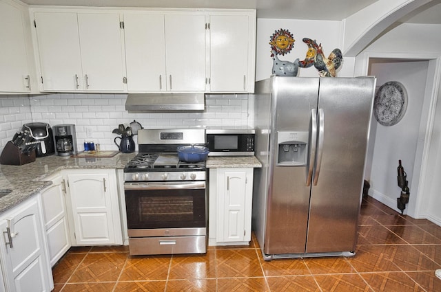 kitchen with white cabinets, light stone countertops, appliances with stainless steel finishes, and tasteful backsplash