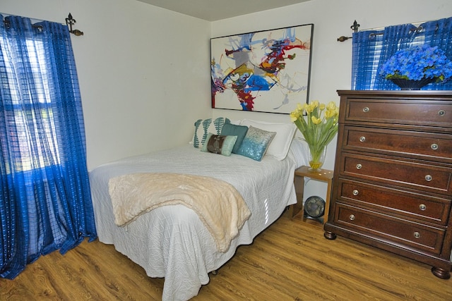 bedroom featuring multiple windows and dark hardwood / wood-style flooring