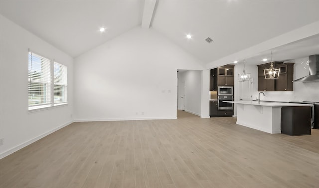 unfurnished living room with sink, beam ceiling, light hardwood / wood-style floors, and high vaulted ceiling