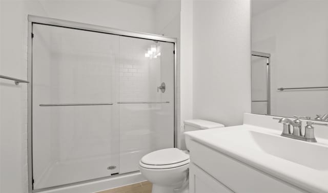 bathroom featuring an enclosed shower, vanity, and toilet