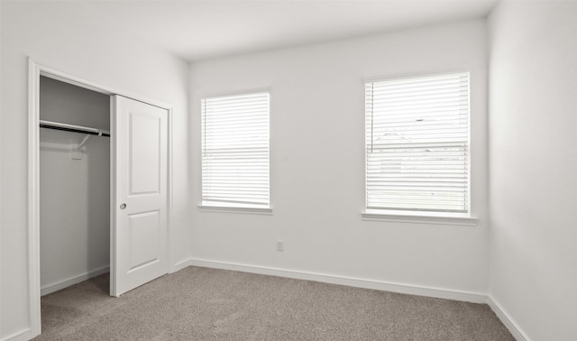 unfurnished bedroom featuring light carpet and a closet