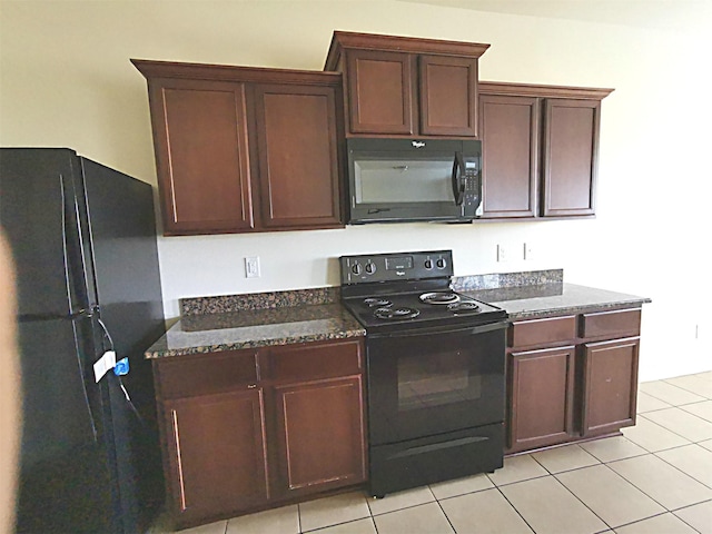 kitchen with dark stone counters, light tile patterned floors, and black appliances