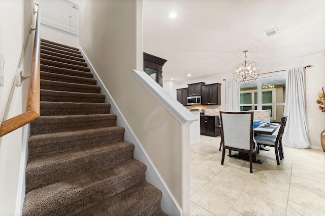 staircase featuring ornamental molding and an inviting chandelier