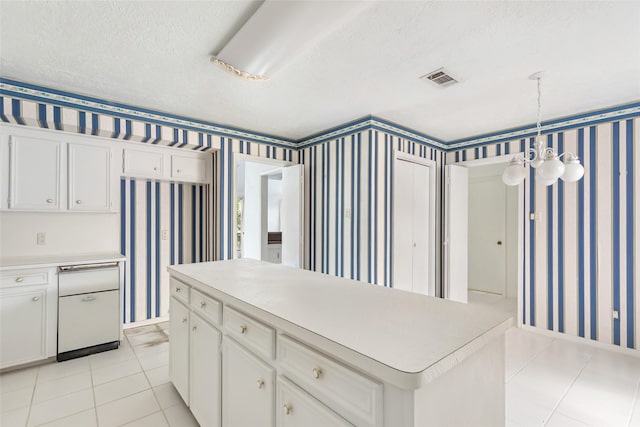 kitchen with a textured ceiling, a kitchen island, a notable chandelier, white cabinetry, and hanging light fixtures