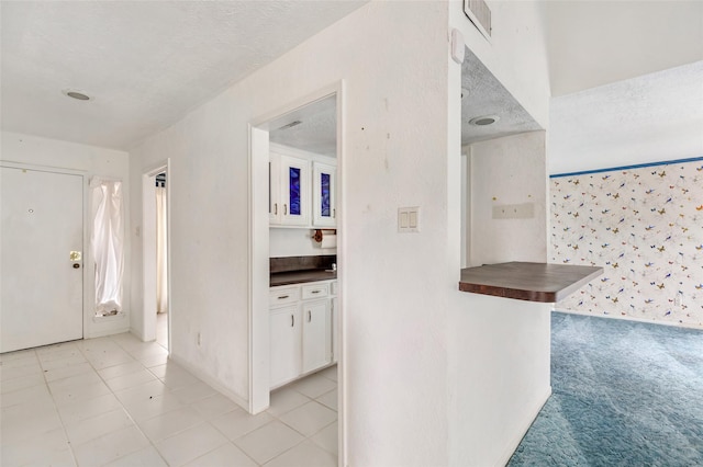 foyer with light colored carpet and a textured ceiling