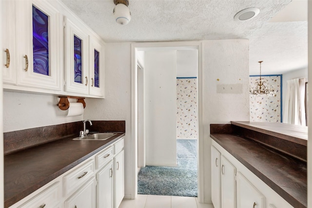 kitchen with white cabinetry, sink, and a textured ceiling