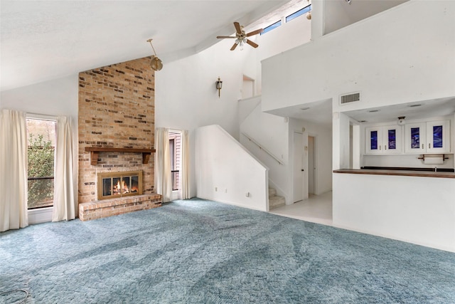 unfurnished living room with a brick fireplace, light colored carpet, high vaulted ceiling, and ceiling fan