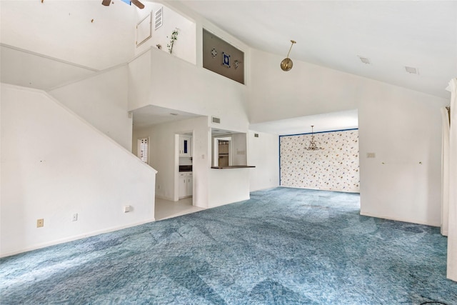 unfurnished living room with ceiling fan with notable chandelier, carpet floors, and high vaulted ceiling