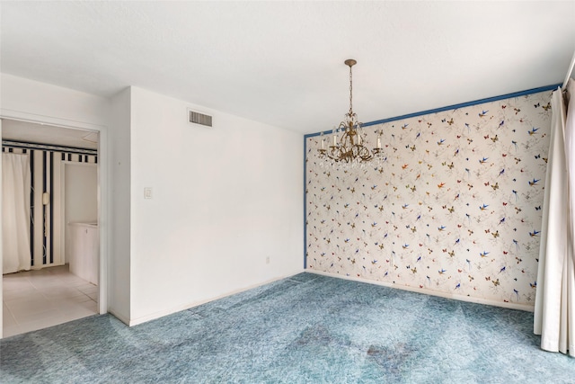 empty room featuring carpet flooring and a chandelier