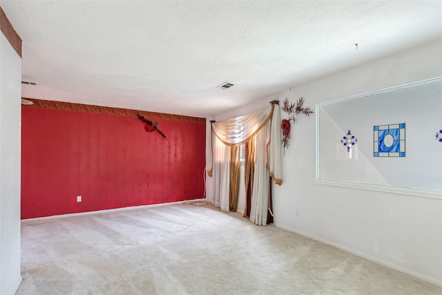 unfurnished room with carpet and a textured ceiling