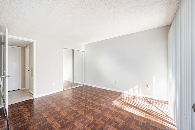 unfurnished bedroom featuring a textured ceiling, a closet, and dark parquet floors