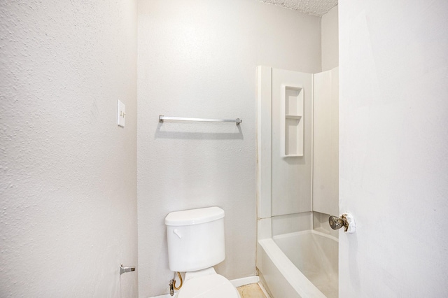 bathroom with a textured ceiling, toilet, and a tub to relax in