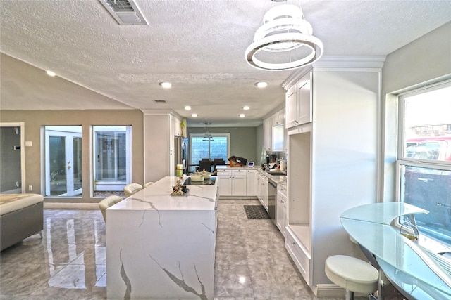 kitchen featuring white cabinets, appliances with stainless steel finishes, decorative light fixtures, light stone counters, and a chandelier