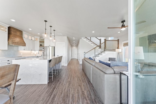 living room featuring ceiling fan, sink, and hardwood / wood-style flooring