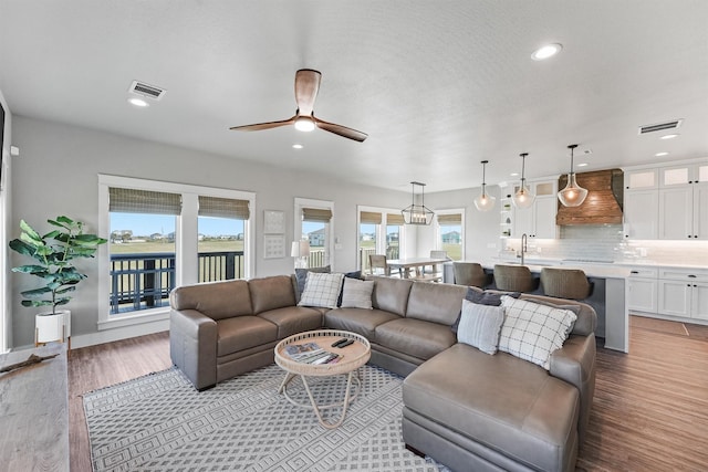 living room with a textured ceiling, ceiling fan, light hardwood / wood-style floors, and sink