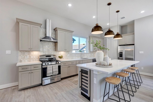 kitchen with beverage cooler, wall chimney range hood, pendant lighting, gray cabinets, and appliances with stainless steel finishes