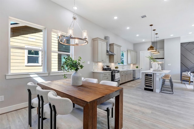 dining space with wine cooler, light hardwood / wood-style flooring, a notable chandelier, and sink