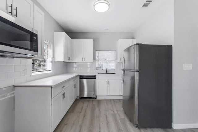 kitchen with light hardwood / wood-style floors, white cabinetry, sink, and appliances with stainless steel finishes