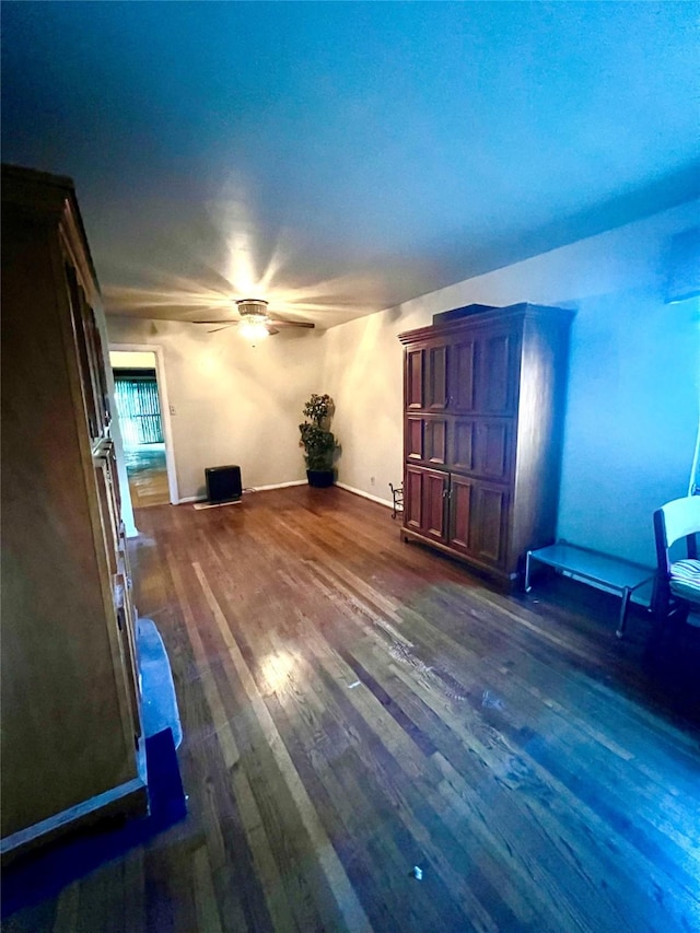 unfurnished living room featuring ceiling fan and dark hardwood / wood-style flooring