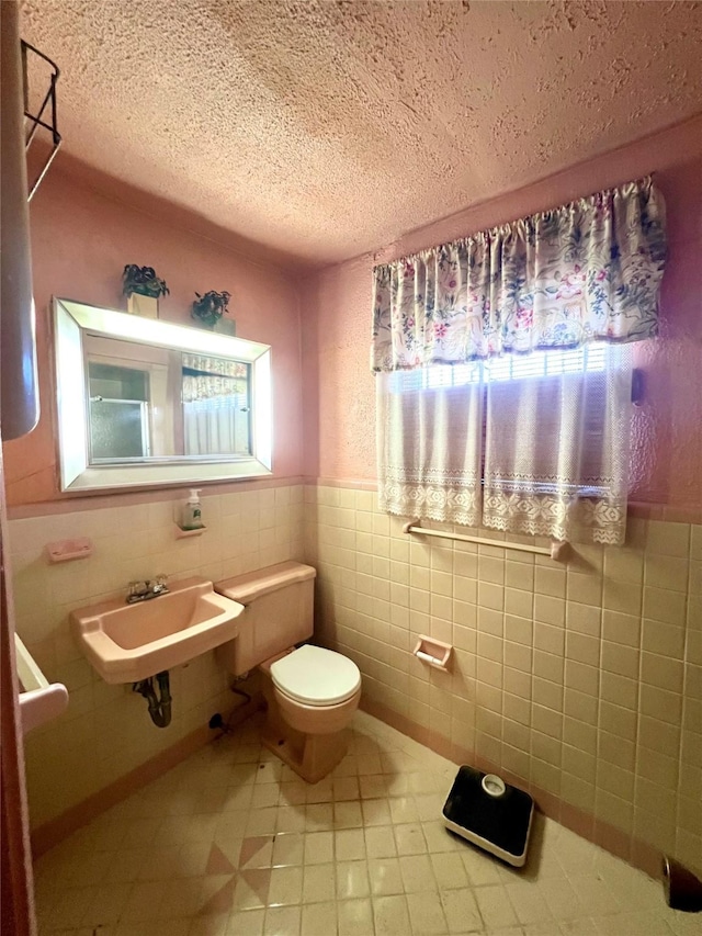 bathroom with sink, a healthy amount of sunlight, a textured ceiling, and toilet