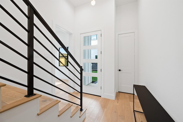 entryway with light hardwood / wood-style flooring and a towering ceiling