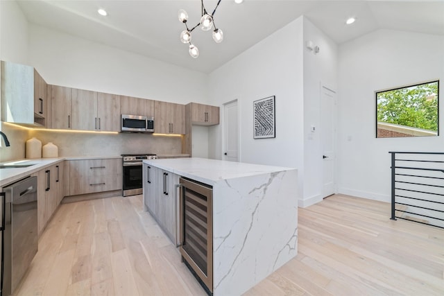 kitchen featuring stainless steel appliances, beverage cooler, light hardwood / wood-style flooring, a center island, and lofted ceiling