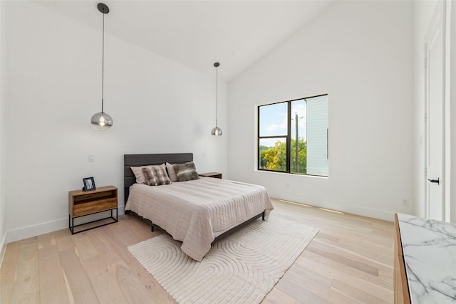 bedroom with light wood-type flooring and high vaulted ceiling