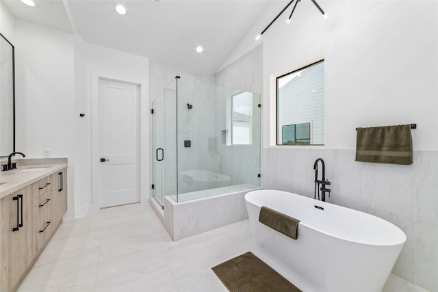 bathroom featuring vanity, vaulted ceiling, tile walls, and separate shower and tub