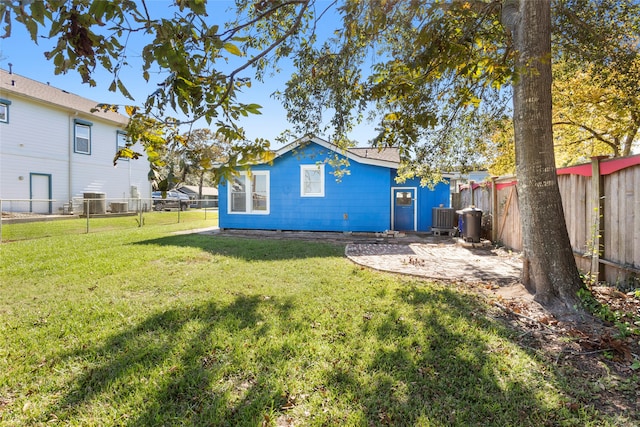 rear view of property featuring central AC unit and a yard