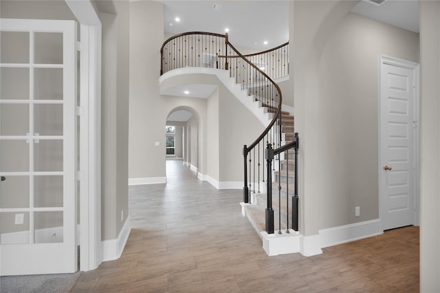 foyer entrance with light wood-type flooring and a towering ceiling