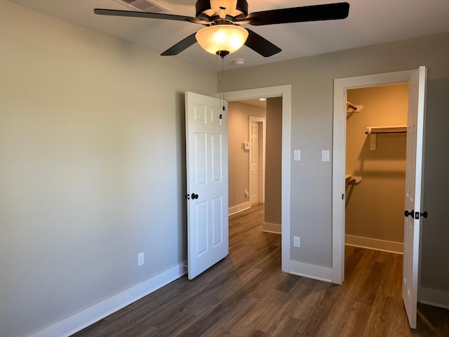 unfurnished bedroom with a closet, dark hardwood / wood-style floors, a spacious closet, and ceiling fan