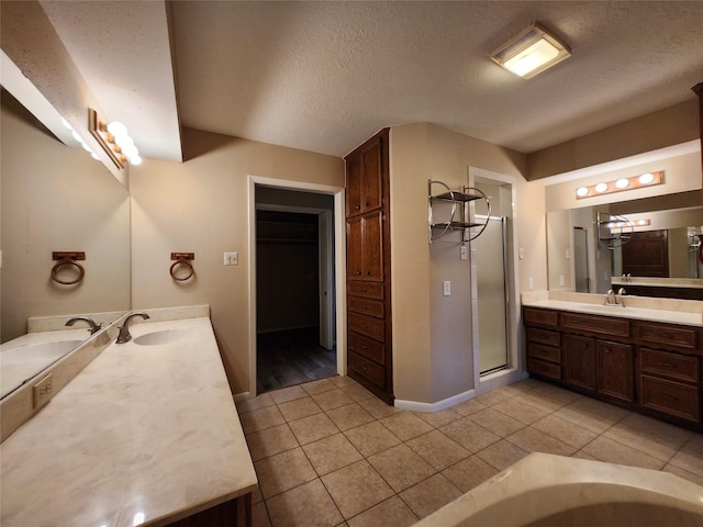 bathroom with tile patterned flooring, vanity, a textured ceiling, and walk in shower